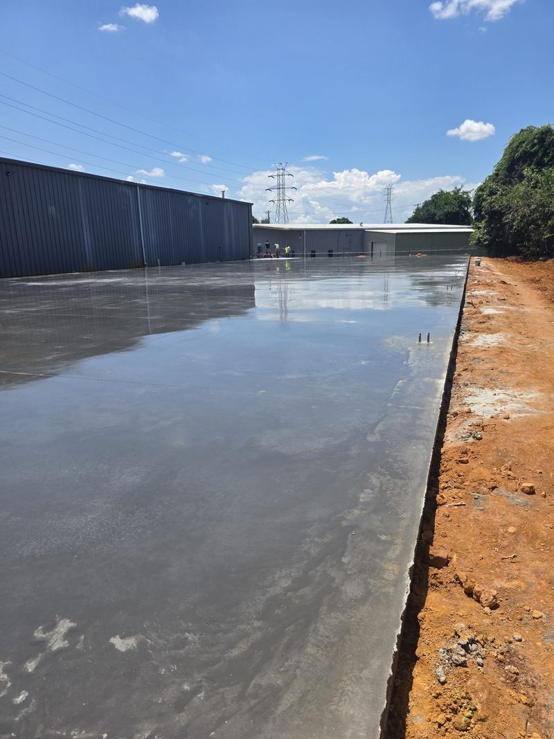 Freshly poured commercial concrete slab next to a metal building