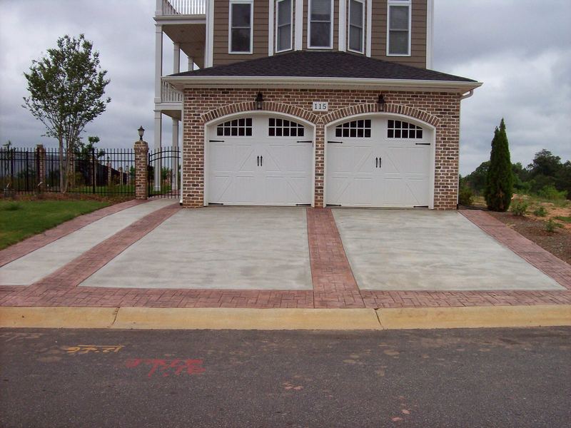 Concrete driveway with stamped brick-pattern borders in front of a brick two-car garage