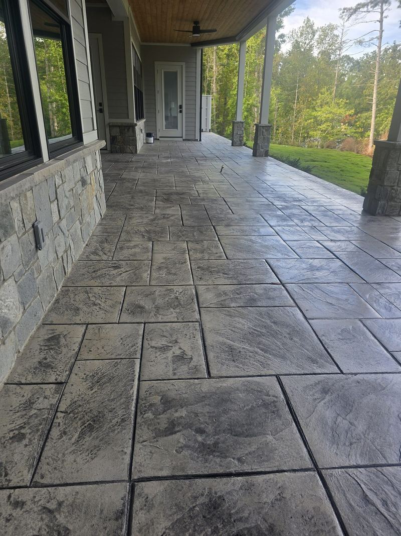 Gray stamped concrete covered porch along a stone-faced house