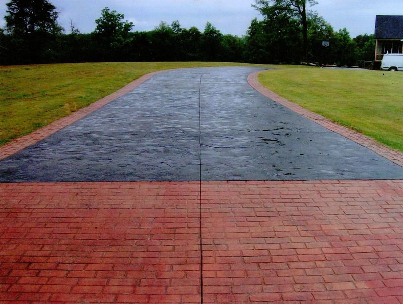 Two-tone stamped concrete driveway with a red brick-pattern apron across a wide lawn